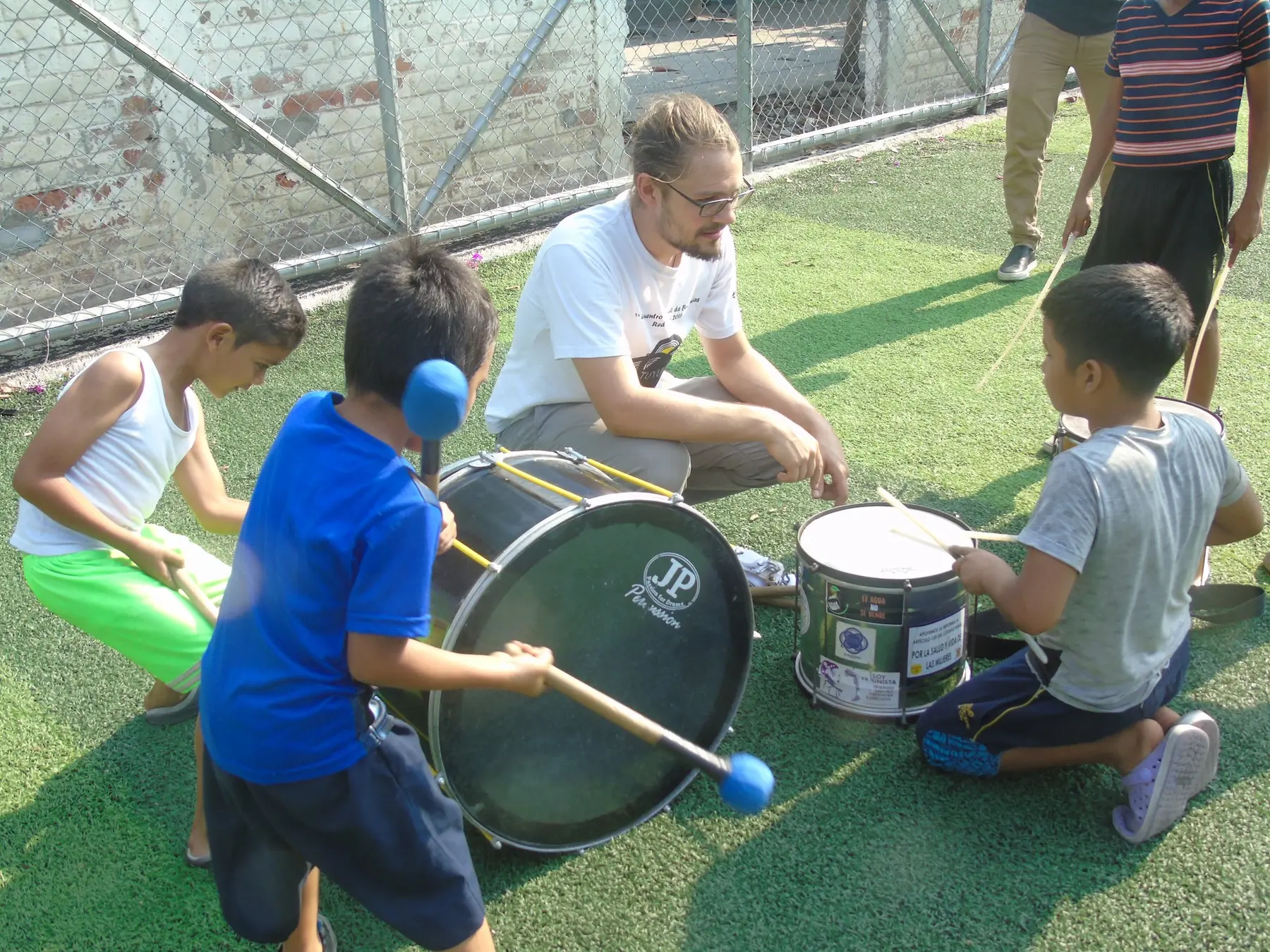 Niños aprenden percusión acompañados por una persona facilitadora