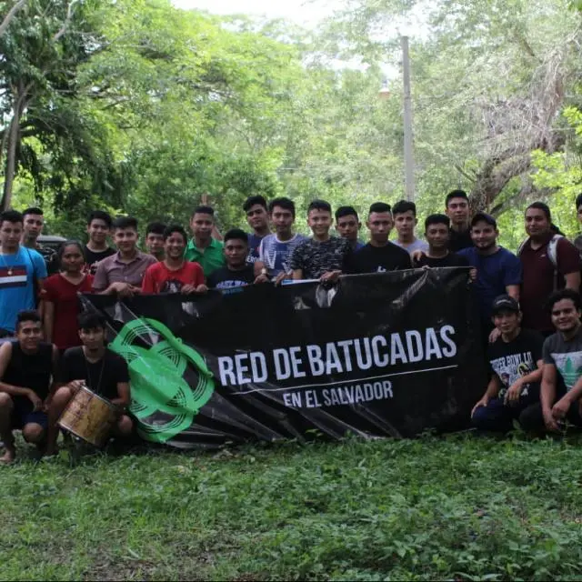 Jóvenes sostienen una pancarta de la Red de Batucadas en El Salvador